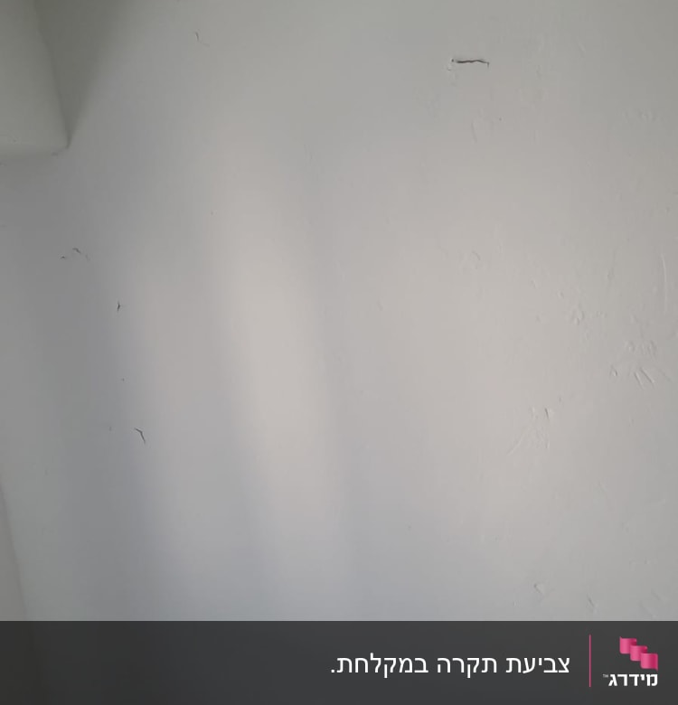 קיר לבן עם סימני צבע ותיקונים